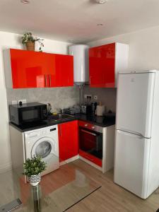 倫敦的住宿－133 Cornwall Road n15 5ax，厨房配有红色橱柜和白色冰箱