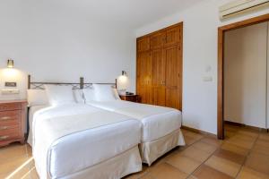 a bedroom with a large white bed and a wooden cabinet at Hostal La Muralla in Zahara de los Atunes