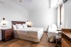 a bedroom with a bed and a desk and a chair at Hostal La Muralla in Zahara de los Atunes
