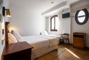 a hotel room with a bed and a window at Hostal La Muralla in Zahara de los Atunes +5 photos