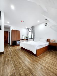 Schlafzimmer mit einem großen weißen Bett und Holzböden in der Unterkunft Happy Bun Hotel Da Lat in Da Lat