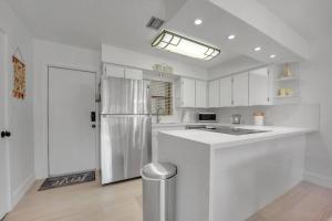 a kitchen with white cabinets and a refrigerator at Overlooking Lagoon and Pool-Free Golf Cart-Kayaks in Key Largo