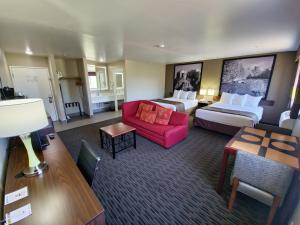 ウィッケンバーグにあるSuper 8 by Wyndham Wickenburg AZのベッド2台と赤いソファが備わるホテルルームです。