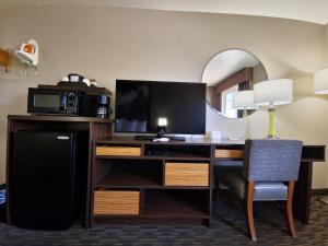 a hotel room with a desk with a microwave and a television at Super 8 by Wyndham Wickenburg AZ in Wickenburg