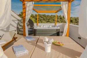 a table on a balcony with a hot tub at Villa Esquel - Beachfront, heated pool in Ražanj