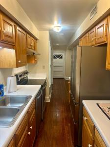 La cuisine est équipée d'armoires en bois et d'un réfrigérateur en acier inoxydable. dans l'établissement Fully furnished garden apartment, à Savannah