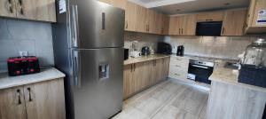 a stainless steel refrigerator in a kitchen with wooden cabinets at Pensiunea Valea Toplitei in Roşia