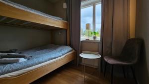 a bedroom with a bunk bed with a chair and a window at Ottsjö Wärdshus in Undersåker