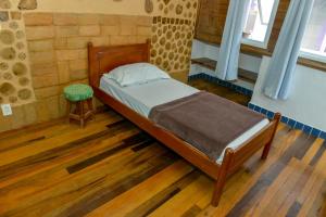 um pequeno quarto com uma cama e um banco em Verde Vida Ecopousada - Termas do Gravatal em Gravatal