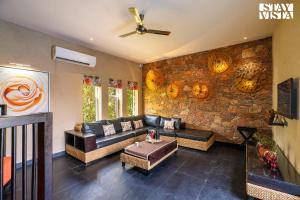 a living room with a couch and a stone wall at StayVista at Poetry by Rawai - Pushkar in Pushkar