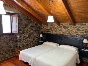 2 camas en una habitación con una pared de piedra en Casa Rural Dona María, en Ordes
