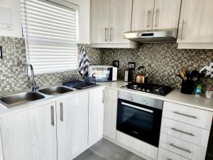 a kitchen with white cabinets and a sink and a stove at Ocean View Villa - Upper in St. Helena Bay