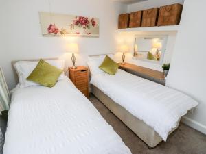 two beds in a room with a mirror at Fleece Cottage in Holmfirth