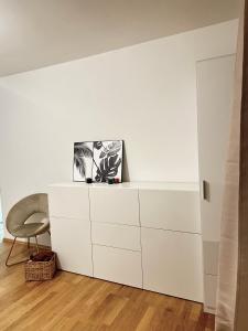 un armario blanco en una habitación con silla en FMI Apartmets next to Frankfurt Airport, en Frankfurt