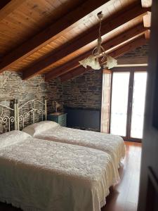 a bedroom with two beds and a stone wall at Casa Rural Dona María in Ordes