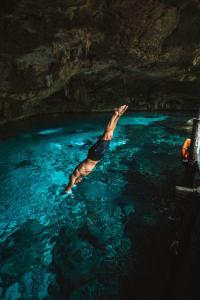 um homem nadando na água em uma caverna em Treehouse Tulum H2Ojos em Tulum