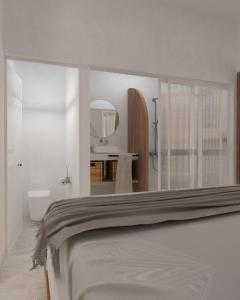 プラタニアスにあるVarouxakis Hotelの白いベッドルーム(ベッド1台、鏡付)