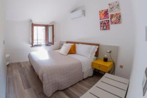 una camera con un letto bianco e un tavolo giallo di SIDORO - Casa Vacanze Torre del Colle a Bevagna