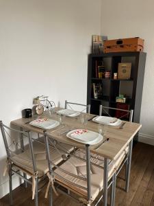 einem Holztisch mit Stühlen und Tellern darauf in der Unterkunft Logement calme + stationnement in Troyes