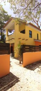 una casa amarilla con una valla delante de ella en Hotel Tabasco en Playa Flamingo