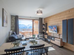 a living room with a table and chairs and a television at Appartement lumineux avec parking, proche des pistes à Alpe d'Huez - FR-1-645-62 in LʼHuez