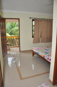 a bedroom with a bed and a window and a door at Minria Guest House in Benaulim