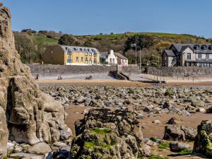 uma praia rochosa com casas e edifícios ao fundo em 3 bed in Pendine 82383 em Pendine