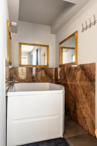 a bathroom with a white tub and two mirrors at Romantic Jacuzzi Studio in Cluj-Napoca