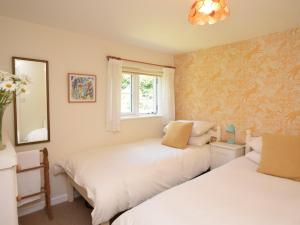 two beds in a bedroom with yellow wallpaper at 4 Bed in Litton Cheney 75851 in Long Bredy