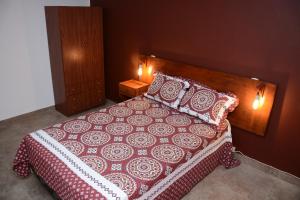 a bedroom with a bed with a red and white bedspread and pillows at La casita de Sue solo para familias reserva solo con seña in Mar del Plata