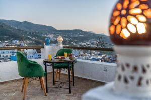 una mesa y sillas en un balcón con vistas en Dar Bleu main en Xauen