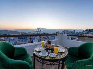 a table with food and orange juice on a balcony at Dar Bleu main in Chefchaouene