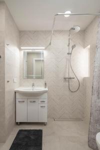 baño blanco con ducha y lavamanos en VAVA apartment, en Klaipėda