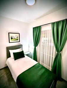 a bedroom with a bed with green curtains and a window at Hotel Genta in Salzburg