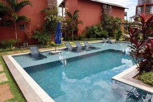 a swimming pool with chairs and a building at Pousada Vila Camurim in Atins