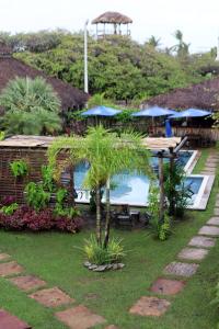un complexe avec une piscine, une table et un parasol dans l'établissement Pousada Vila Camurim, à Atins