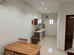 a kitchen with a wooden table and chairs in a room at الرصافة الجنوبية للشقق المخدومة in Al Jith