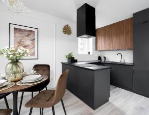 a kitchen with black cabinets and a table and chairs at Flatbook - City Center Apartments Scala Moderna in Gdańsk