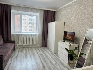a living room with a couch and a refrigerator at Уютная квартира ЖК Сказочный мир город Астана in Astana