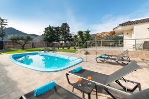 a swimming pool with chairs and a table and a patio at Sugar View Villa In Kolymbia in Kolymbia