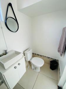 a white bathroom with a toilet and a mirror at DuPai 12 Sorocaba in Sorocaba