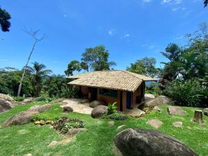 een klein huis in een veld met rotsen bij Bangalô Sol · Bangalô Sol: refúgio c/ vista incrível em Ilhabela in Ilhabela