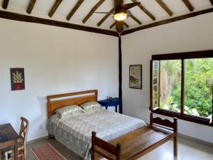 een slaapkamer met een bed, een tafel en een raam bij Bangalô Sol · Bangalô Sol: refúgio c/ vista incrível em Ilhabela in Ilhabela
