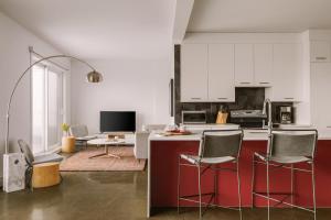 uma cozinha com armários brancos e uma ilha vermelha com cadeiras em Sonder Penny Lane em Montreal