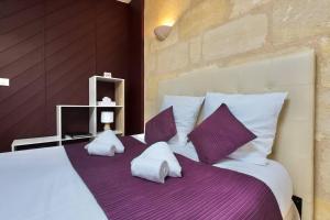 a bedroom with a large bed with purple sheets and pillows at Grand studio à Bordeaux chartrons in Bordeaux