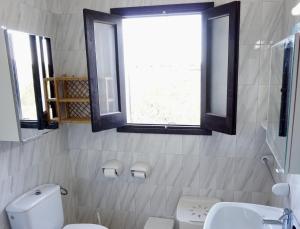 baño con aseo y lavabo y 2 ventanas en Casa Sa Playa - Astbury Formentera, en Es Arenals 20 fotos más