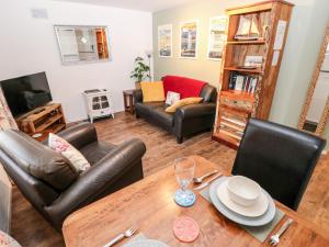 a living room with a table and leather chairs at The Coach House in Tenby