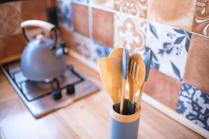 una taza con cucharas de madera y una olla en una estufa en El Secreto en las Sierras, en Villa Serrana