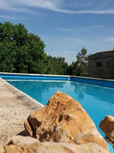 een blauw zwembad met een rots op de voorgrond bij Casa Rural en pleno paraje natural La Chirala in Enguera