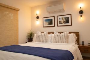 1 dormitorio con 1 cama blanca grande con almohadas blancas en Newport Surf Casita, en Newport Beach